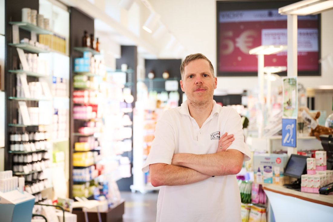 Ein Apotheker steht mit verschränkten Armen im Verkaufsraum
