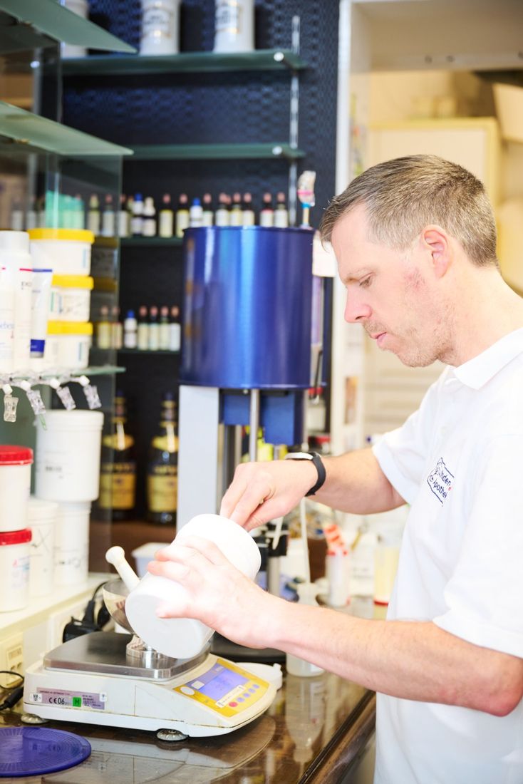 Ein Apotheker rührt in der Rezeptur an einem Rührgerät eine Salbe an